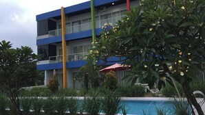 A multi-story hotel with balconies, a swimming pool, and lush greenery. - JEPARA BEACH HOTEL (Tahunan)