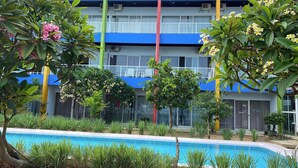 A hotel with a swimming pool, surrounded by greenery and a blue and yellow building facade. - JEPARA BEACH HOTEL (Tahunan)