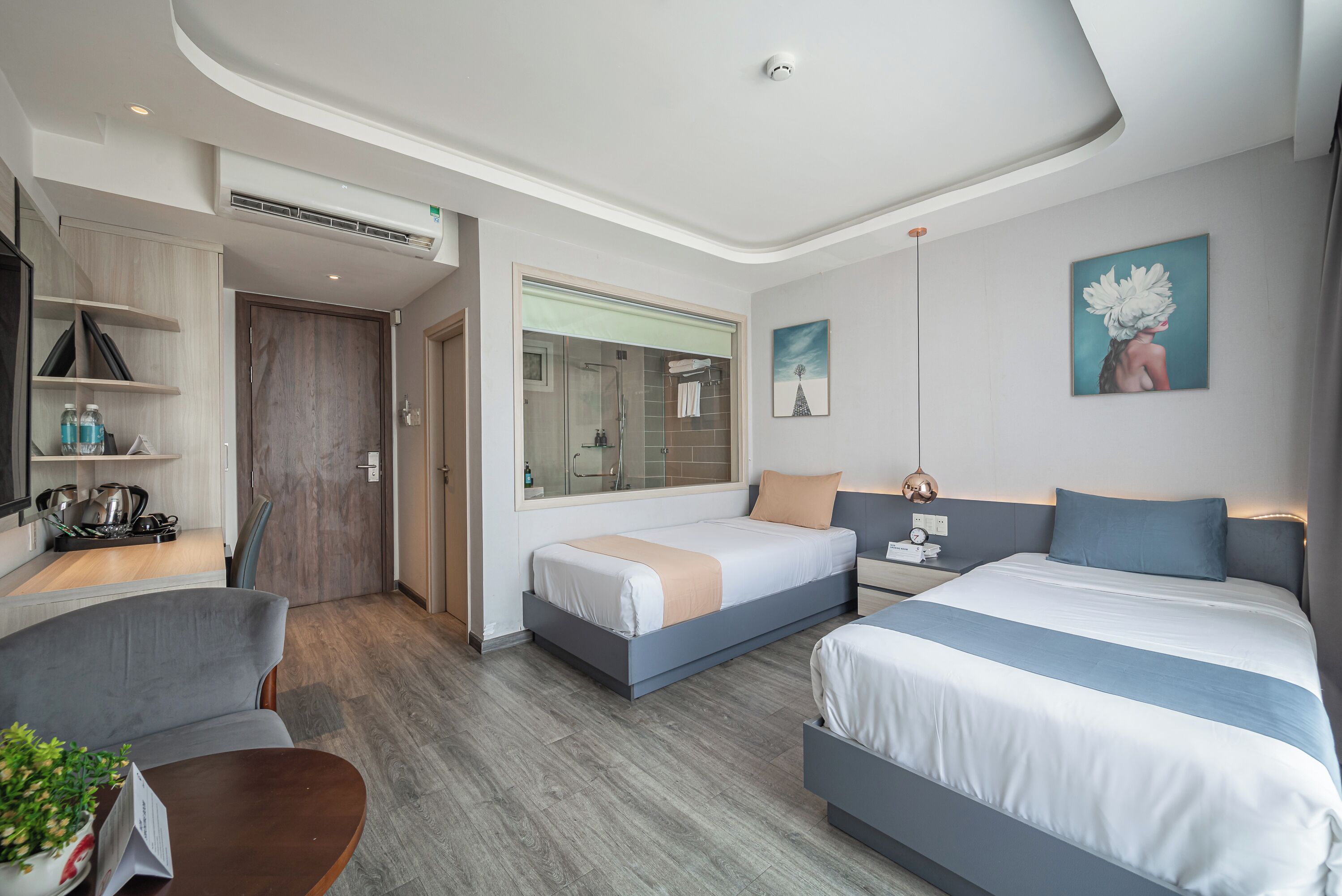 Ein modernes Hotelzimmer mit einem großen Bett, einem Schreibtisch, einem Sessel und einem kleinen Tisch mit einer Pflanze.