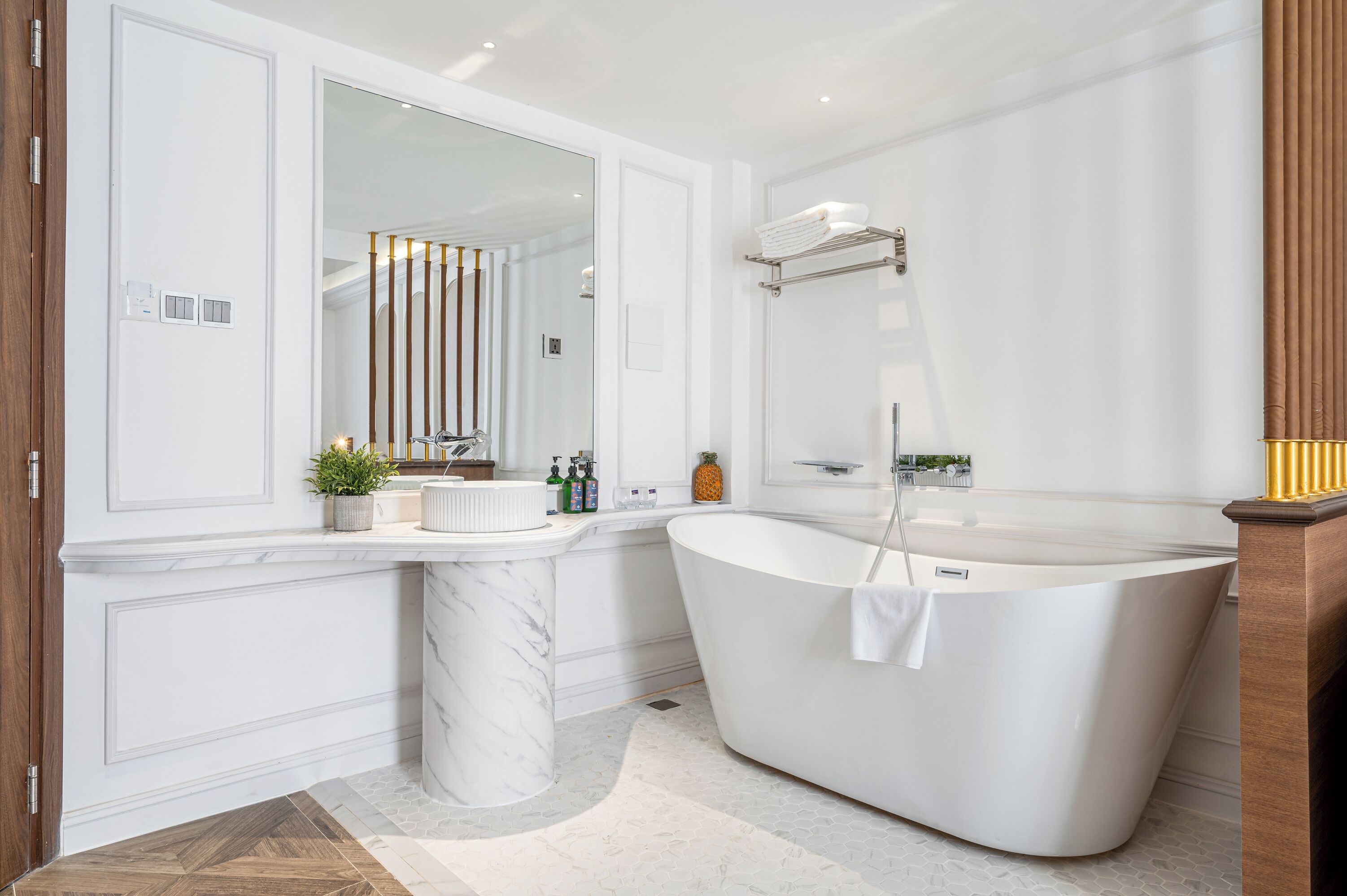 A modern bathroom with a freestanding bathtub, a large mirror, and a marble sink.