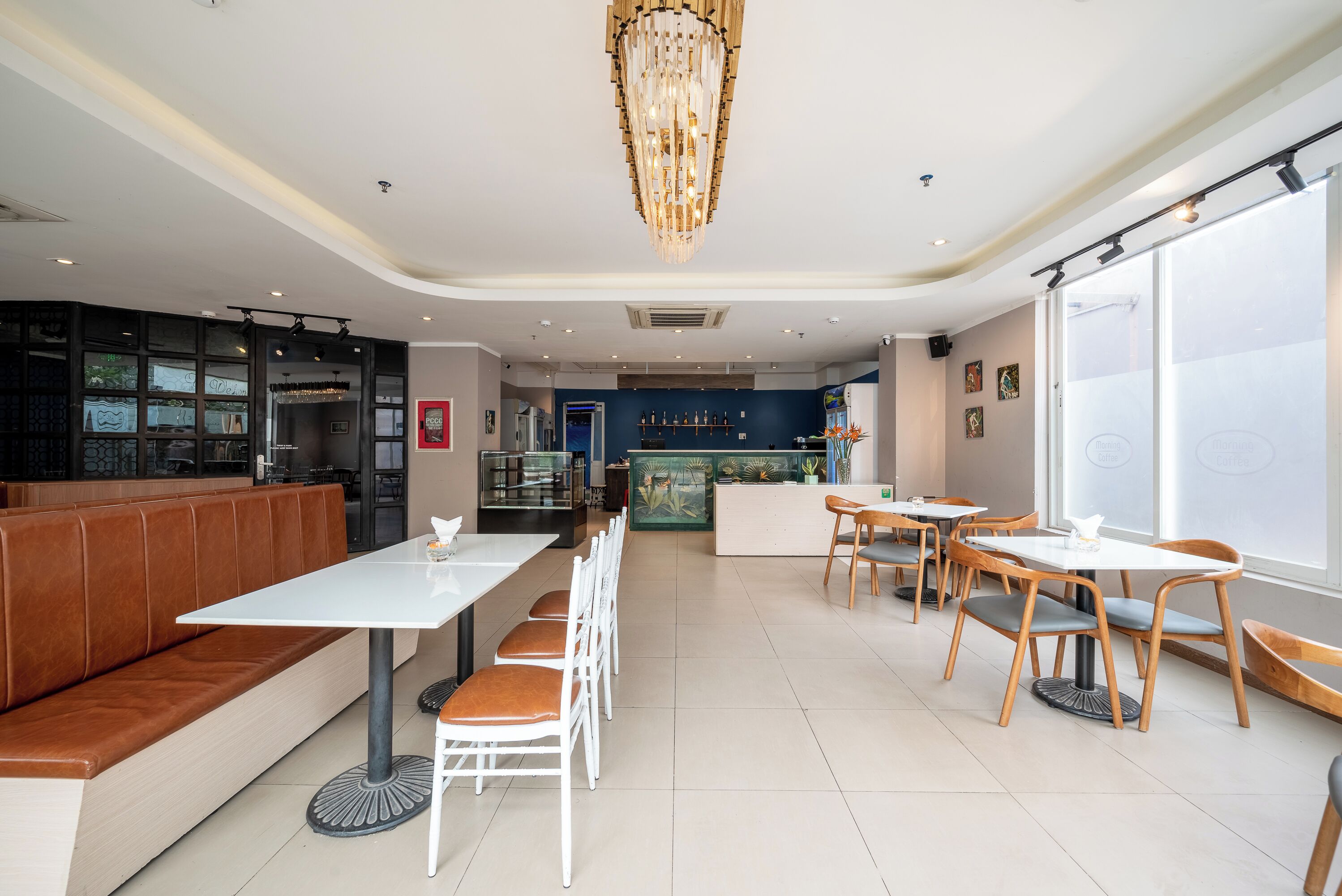 A modern restaurant with a central bar area, seating arrangements, and a large window providing natural light.