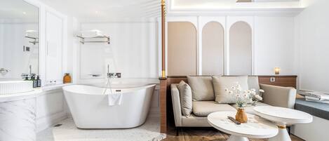 Un baño moderno con una bañera independiente, un espejo grande y un lavamanos de mármol.