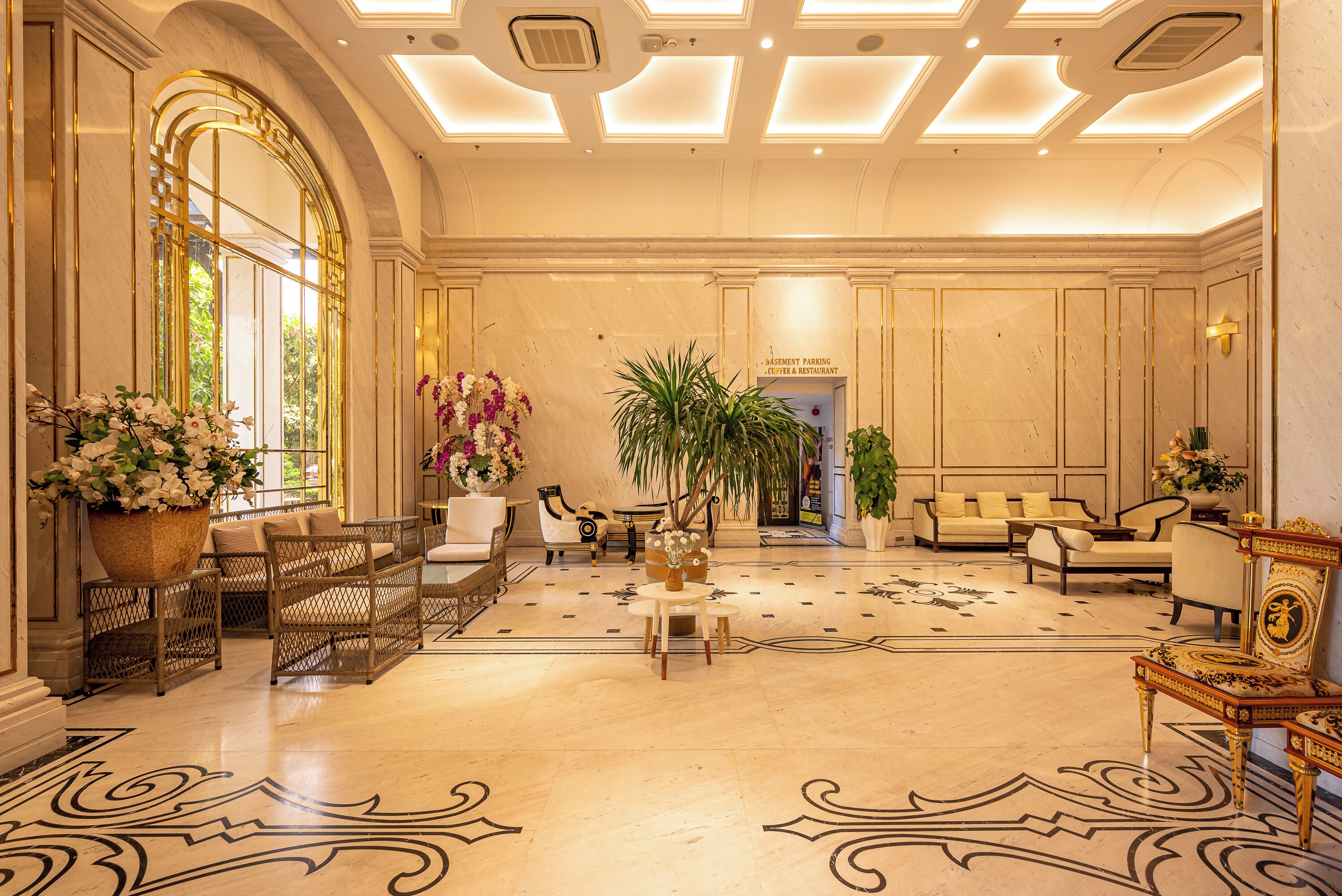 A spacious lobby with a large seating area, a reception desk, and a view of the entrance to the basement parking and restaurant.