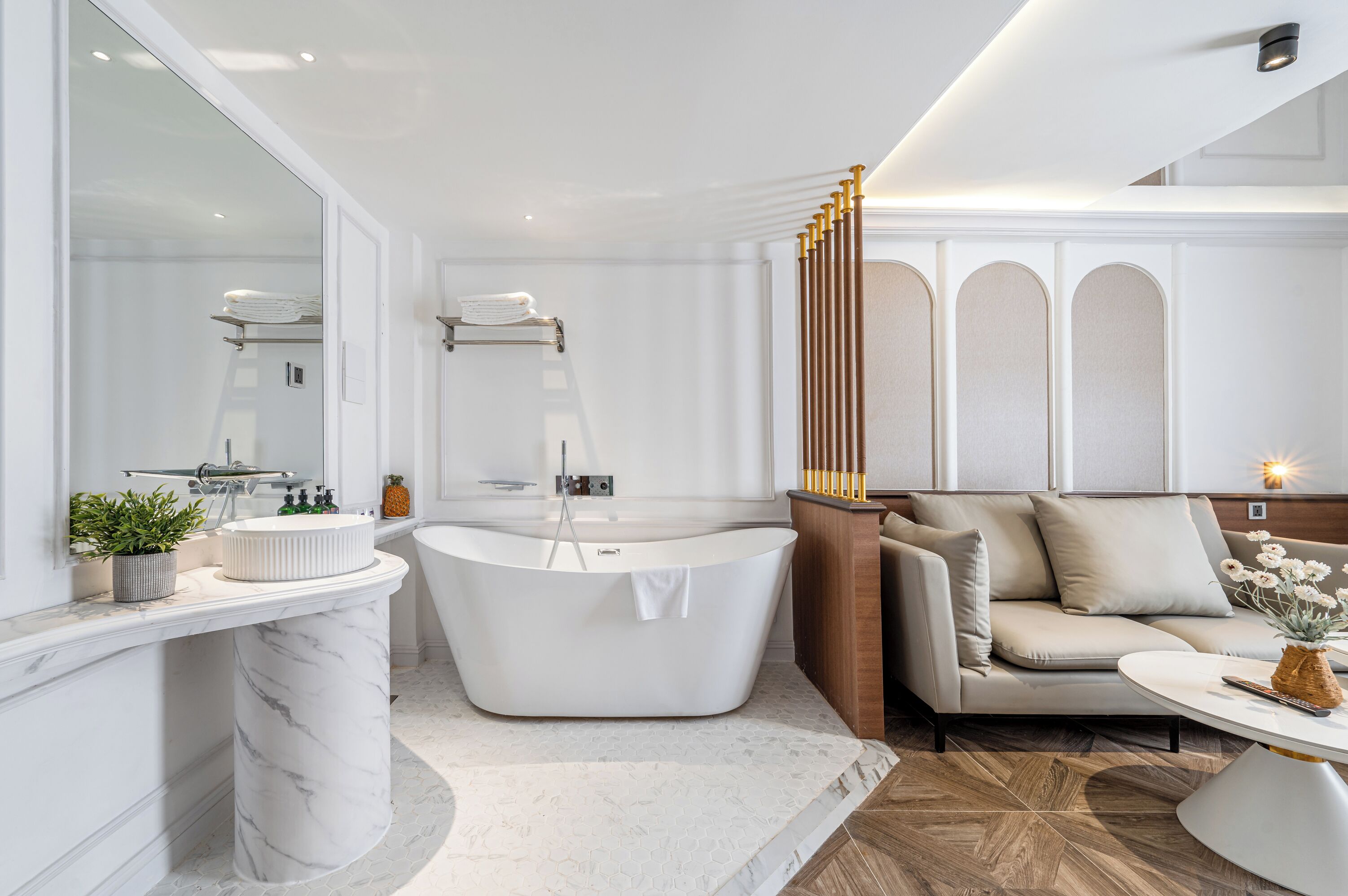 A modern bathroom with a freestanding bathtub, a vanity with a marble countertop, and a large mirror.