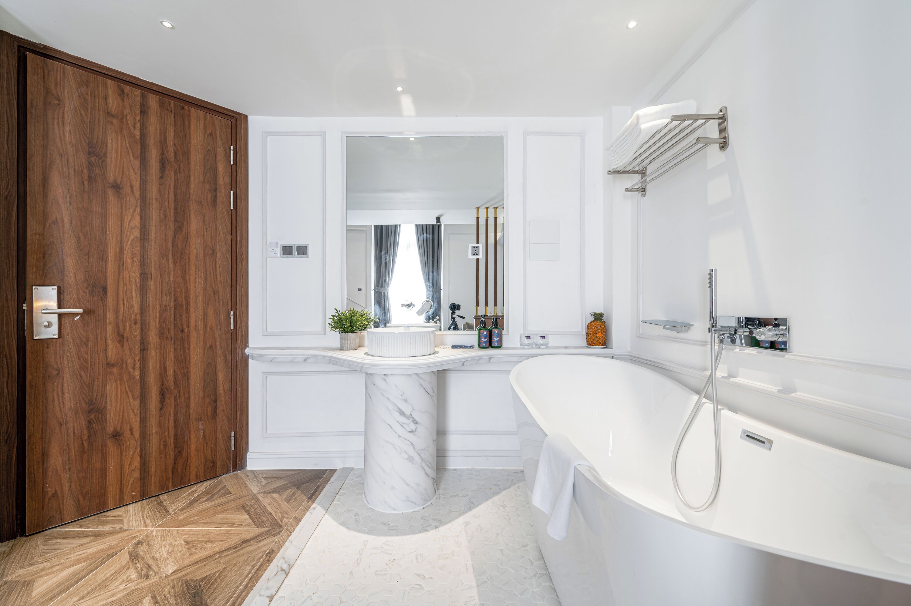 Une salle de bain moderne avec une porte en bois, un lavabo en marbre, une baignoire sur pieds et un miroir au-dessus du lavabo.