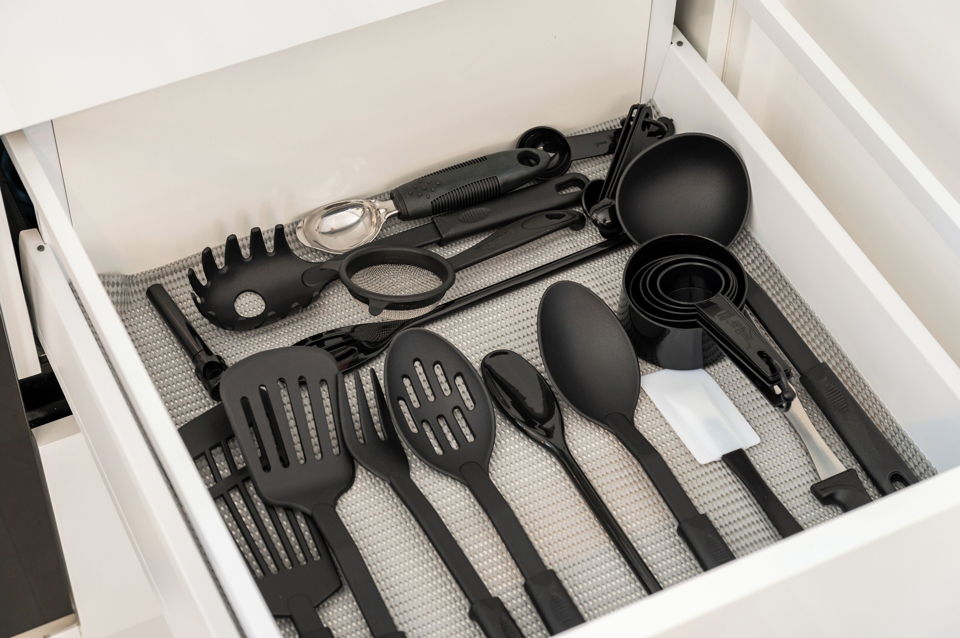 Un cajón con diferentes utensilios de cocina, incluyendo espátulas, pinzas y una cuchara.