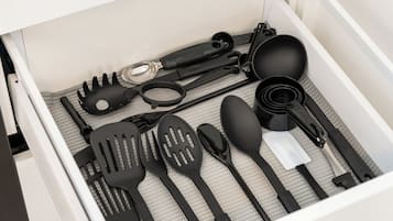 Un cajón con diferentes utensilios de cocina, incluyendo espátulas, pinzas y una cuchara.