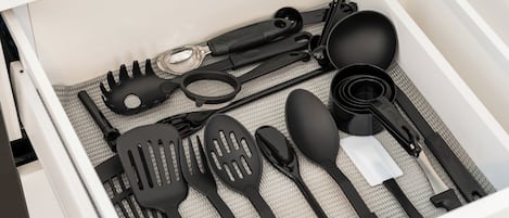 Un cajón con diferentes utensilios de cocina, incluyendo espátulas, pinzas y una cuchara.