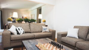 A living room with two sofas, a coffee table with a chess set, and a hallway with potted plants and lamps. - LUXURY IN THE HEART OF ORANGE. 1 MINUTE WALK TO BEST CAFES AND RESTAURANTS (Orange)