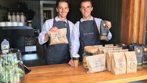 Two individuals in a cafe holding takeaway bags, with a coffee machine and various bags on the counter. - LUXURY IN THE HEART OF ORANGE. 1 MINUTE WALK TO BEST CAFES AND RESTAURANTS (Orange)