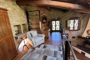A rustic stone interior with a sofa, wooden beams, a staircase, and a fireplace. - My Exclusive Italy - Spacious Villa with Private Pool & Garden near Chianti (Impruneta)