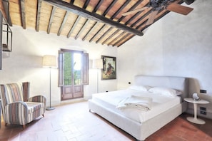 A bedroom with a bed, a chair, a lamp, and a painting on the wall. - My Exclusive Italy - Spacious Villa with Private Pool & Garden near Chianti (Impruneta)
