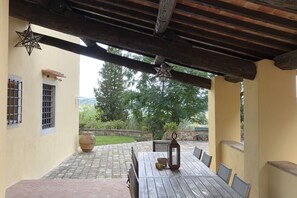 An outdoor patio with a wooden table and chairs, a star lantern, and a view of greenery. - My Exclusive Italy - Spacious Villa with Private Pool & Garden near Chianti (Impruneta)