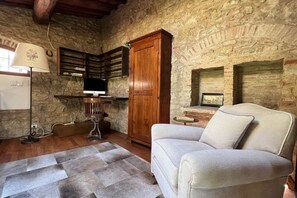 A rustic room with a stone wall, wooden cabinet, and a light-colored sofa. - My Exclusive Italy - Spacious Villa with Private Pool & Garden near Chianti (Impruneta)