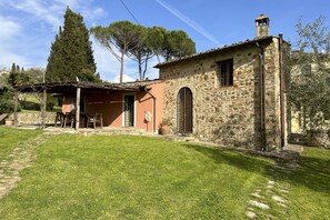 A stone building with a small patio, a chimney, and a garden.