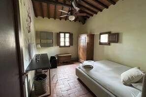 A small, cozy room with a bed, a desk, a chair, a cabinet, and a ceiling fan. - My Exclusive Italy - Spacious Villa with Private Pool & Garden near Chianti (Impruneta)