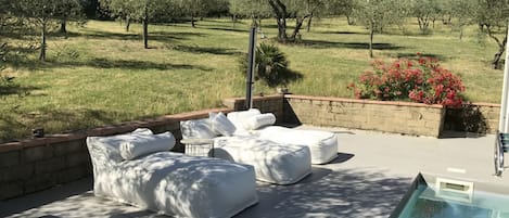 A poolside area with outdoor seating and a view of a grassy landscape.