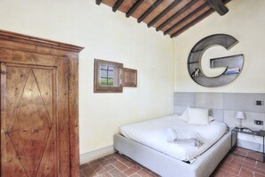 A bedroom with a bed, a wooden wardrobe, a wall-mounted letter 'G', and a small window. - My Exclusive Italy - Spacious Villa with Private Pool & Garden near Chianti (Impruneta)