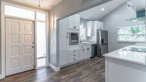Una cocina moderna con armarios blancos, un refrigerador de acero inoxidable y un horno empotrado.