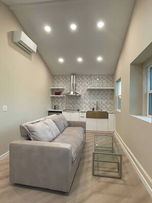 A modern kitchen with a built-in stove, a white countertop, and a stone backsplash.