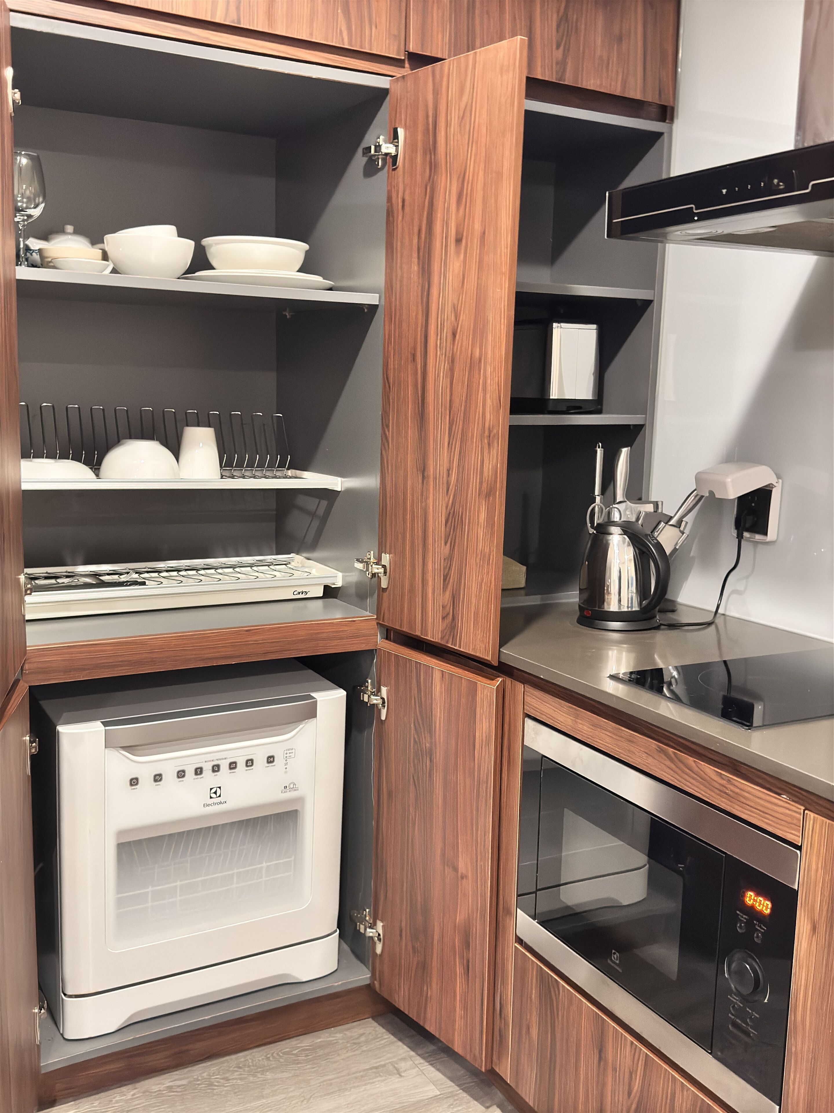 Une cuisine compacte équipée d’un four encastré, d’un four à micro-ondes et d’une machine à café posée sur le plan de travail.