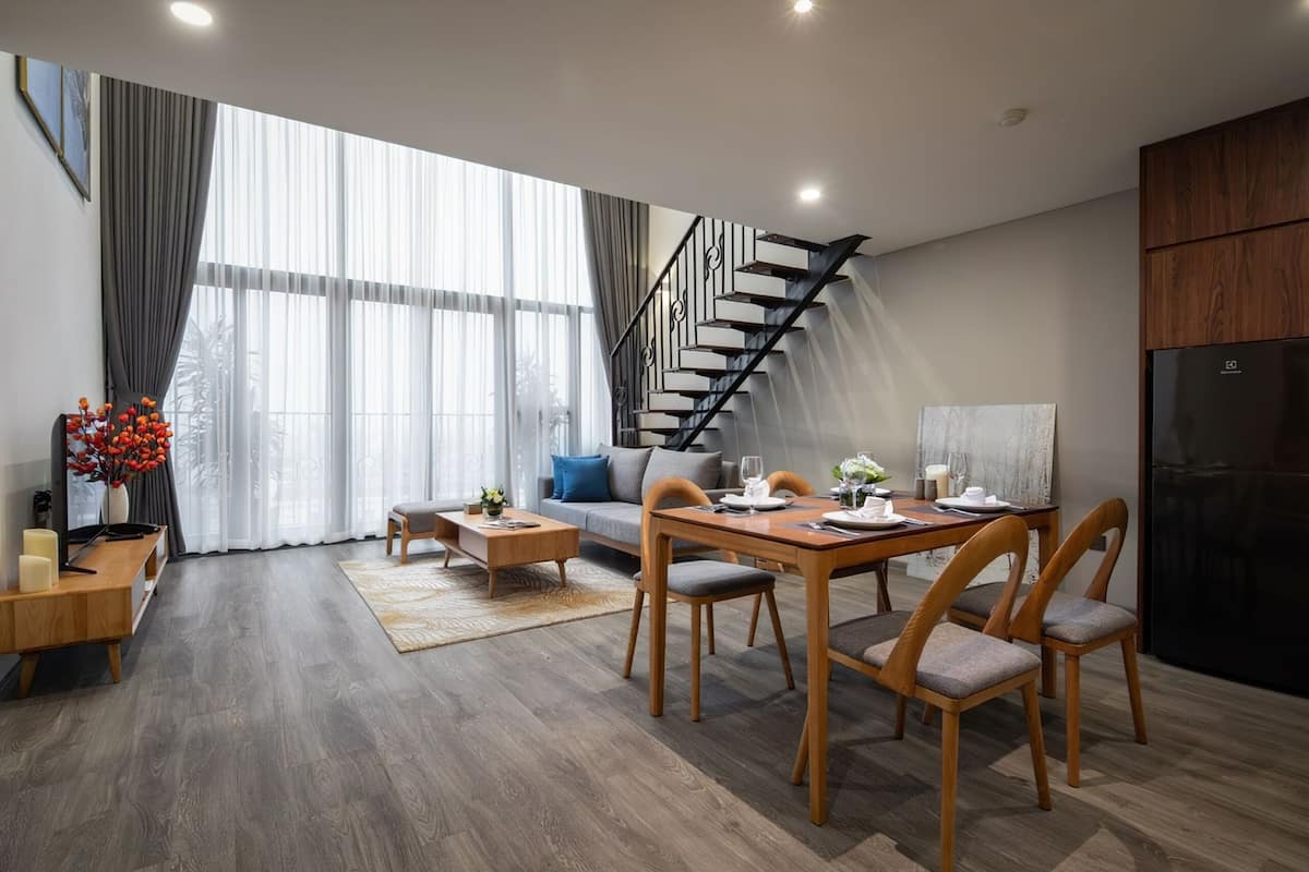 Una sala moderna con comedor, ventanas amplias, una escalera y una cocina.