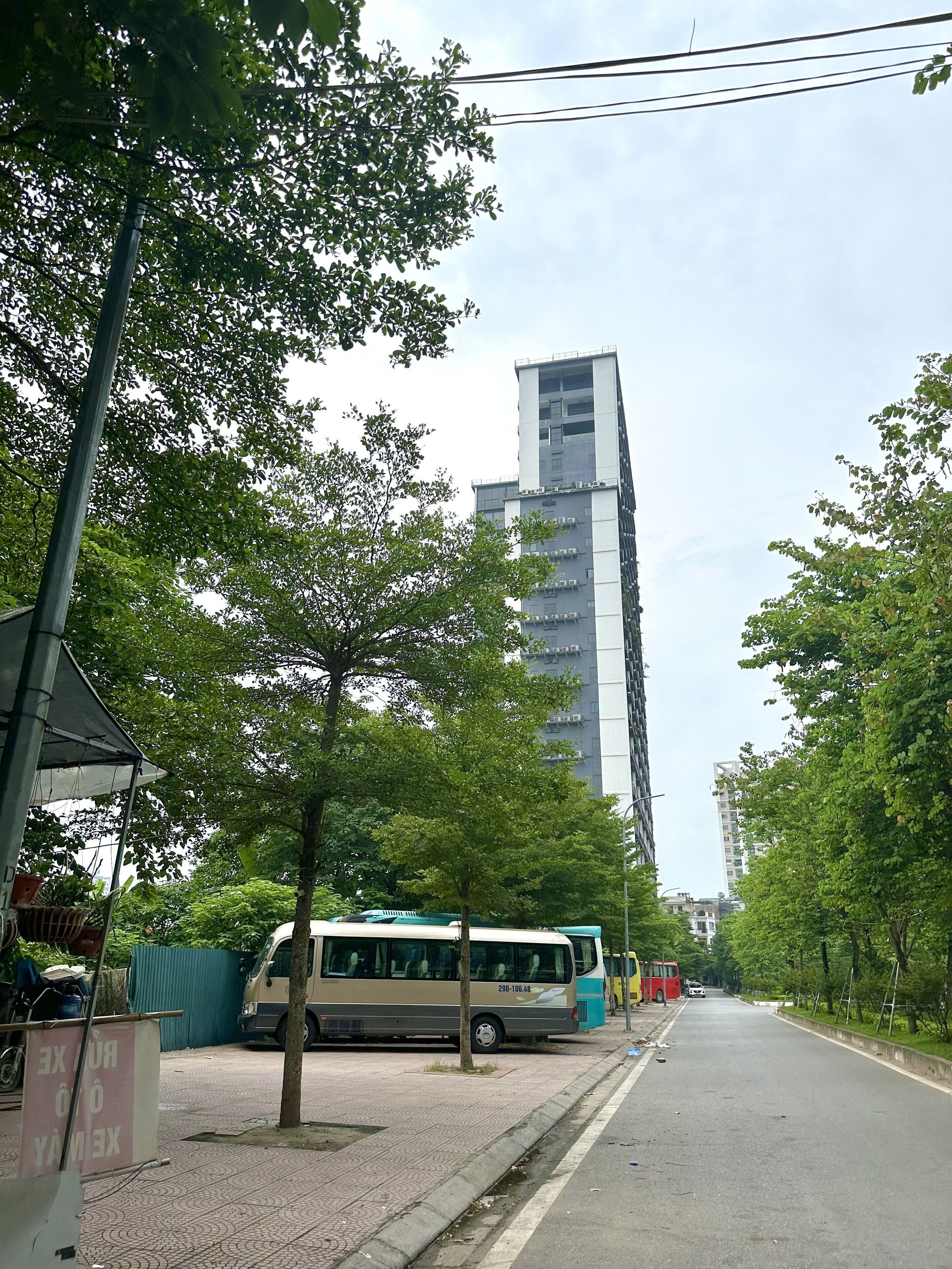 Eine Straße mit einem Bus, Bäumen und einem hohen Gebäude.