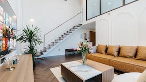 A modern living room with a wooden coffee table, a sofa, and a staircase leading to an upper level. - PentStudio West Lake by Emily in Town (Hanoi)