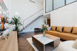 A modern living room with a wooden coffee table, a sofa, and a staircase leading to an upper level.
