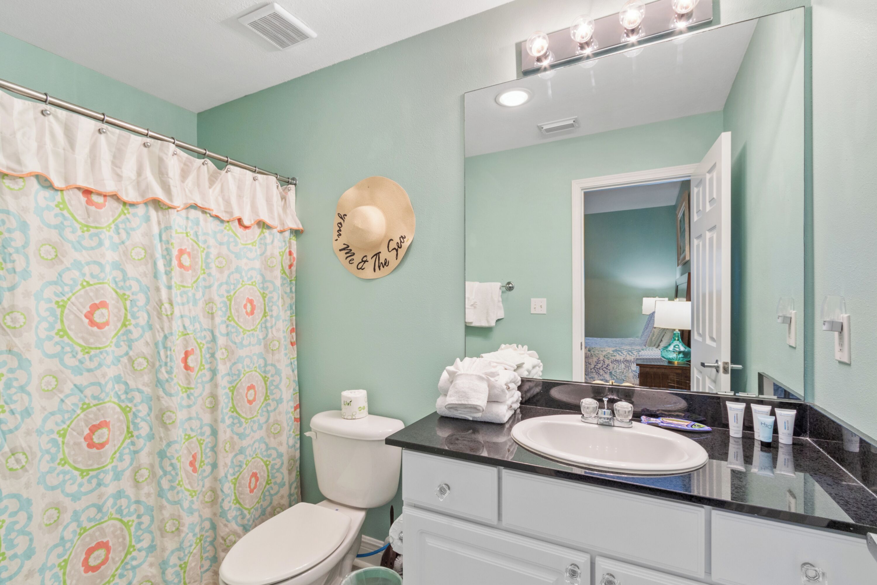 A bathroom with a toilet, sink, and shower curtain.