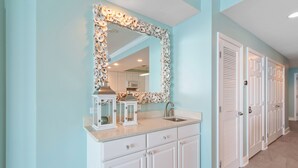 A bathroom with a large mirror, white cabinets, and a sink. - San Carlos 1501 (Gulf Shores)