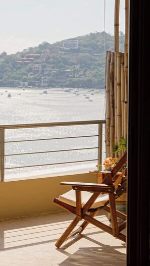 Enjoy breathtaking views of the bay from this balcony, complete with a comfortable chair and a charming table setting.