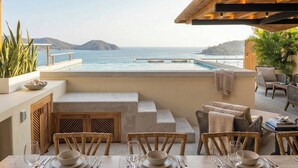 Una terraza con piscina, zona de comedor y asientos con vistas al mar.