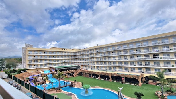 Ein Hotel mit mehreren Balkonen, einem Poolbereich inklusive Rutschen und einem angelegten Garten.