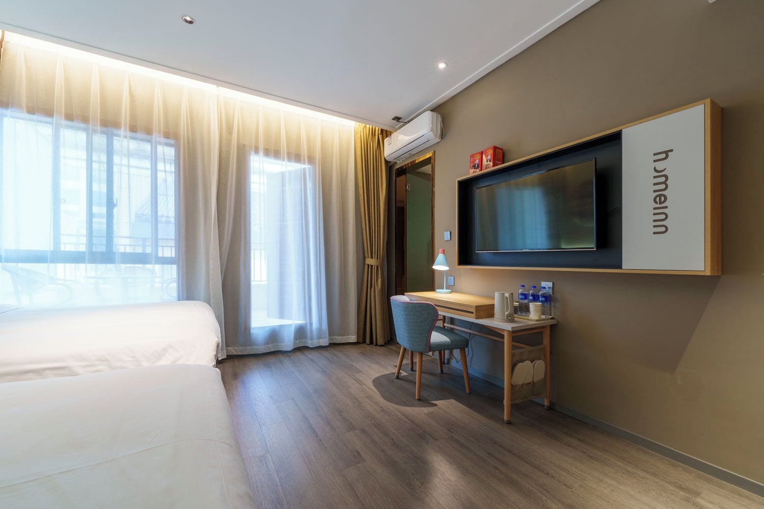 Hotelkamer met een bed, een bureau, een stoel, een televisie en een raam met gordijnen.