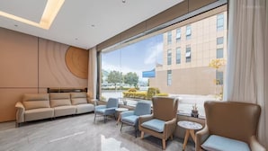 Eine moderne Hotelhalle mit einer Couch, Sesseln und einem Couchtisch.