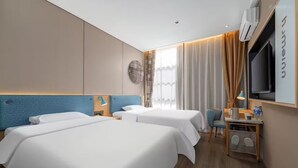 Ein Hotelzimmer mit zwei Betten, einem Schreibtisch mit Stuhl, einem Fernseher und einem Fenster mit Vorhängen.