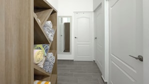 A hallway with a wooden storage unit, a white door, and a grey tiled floor.