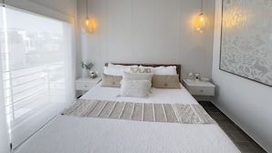 A modern bedroom with a large bed, two bedside tables, a window with a view, and a decorative wall piece.