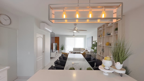 A modern living room with a central island, a dining area, and a kitchen.