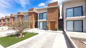 A modern residential building with brick facades, large windows, and a well-maintained lawn.