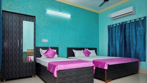 A hotel room with two beds, a wardrobe, a ceiling fan, and an air conditioning unit. - Deb Guest House (Barakpur)