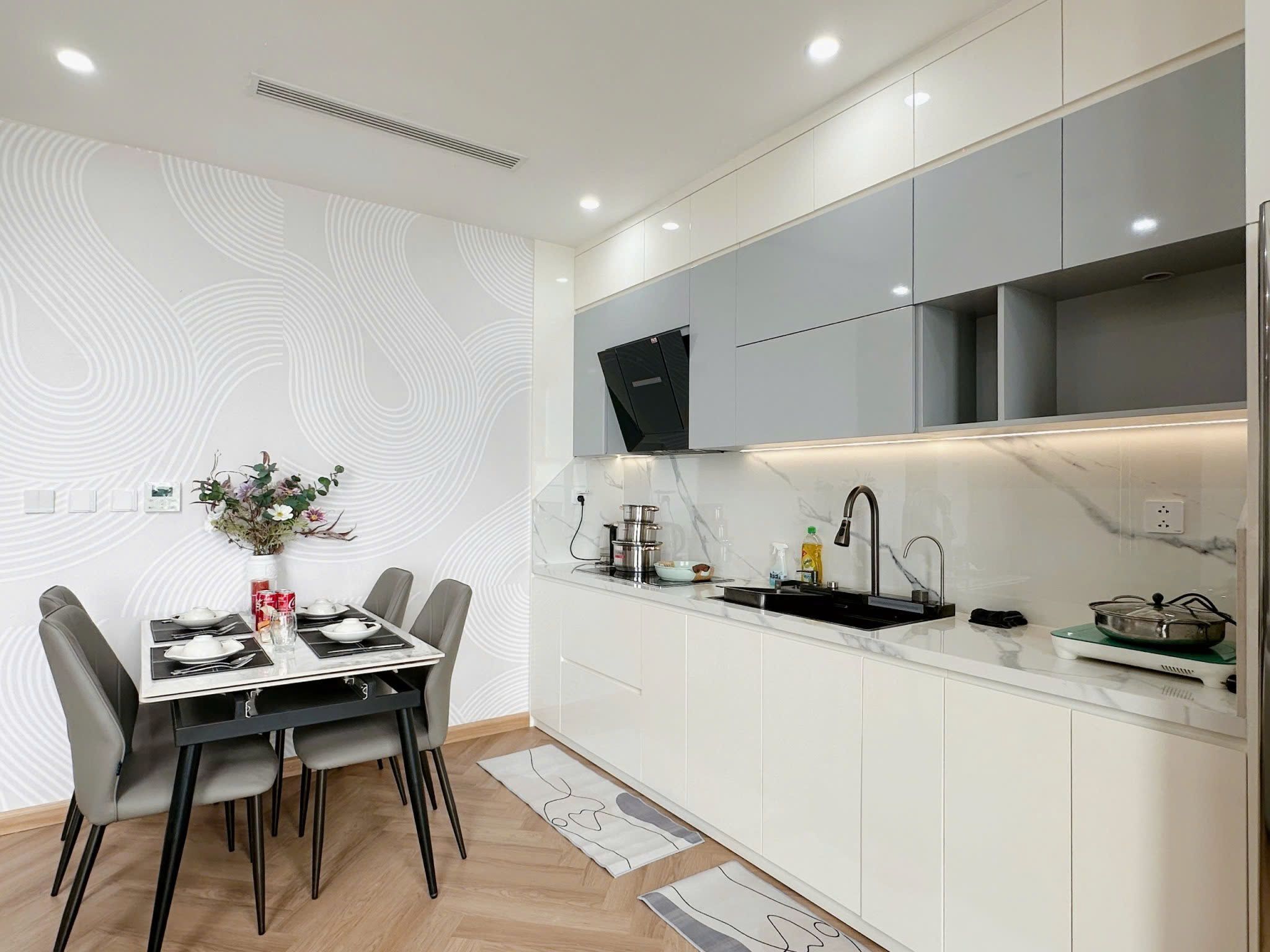 A modern kitchen with white cabinets, a black faucet, and a dining area with a table set for two.