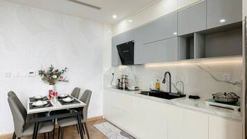 A modern kitchen with white cabinets, a black faucet, and a dining area with a table set for two.