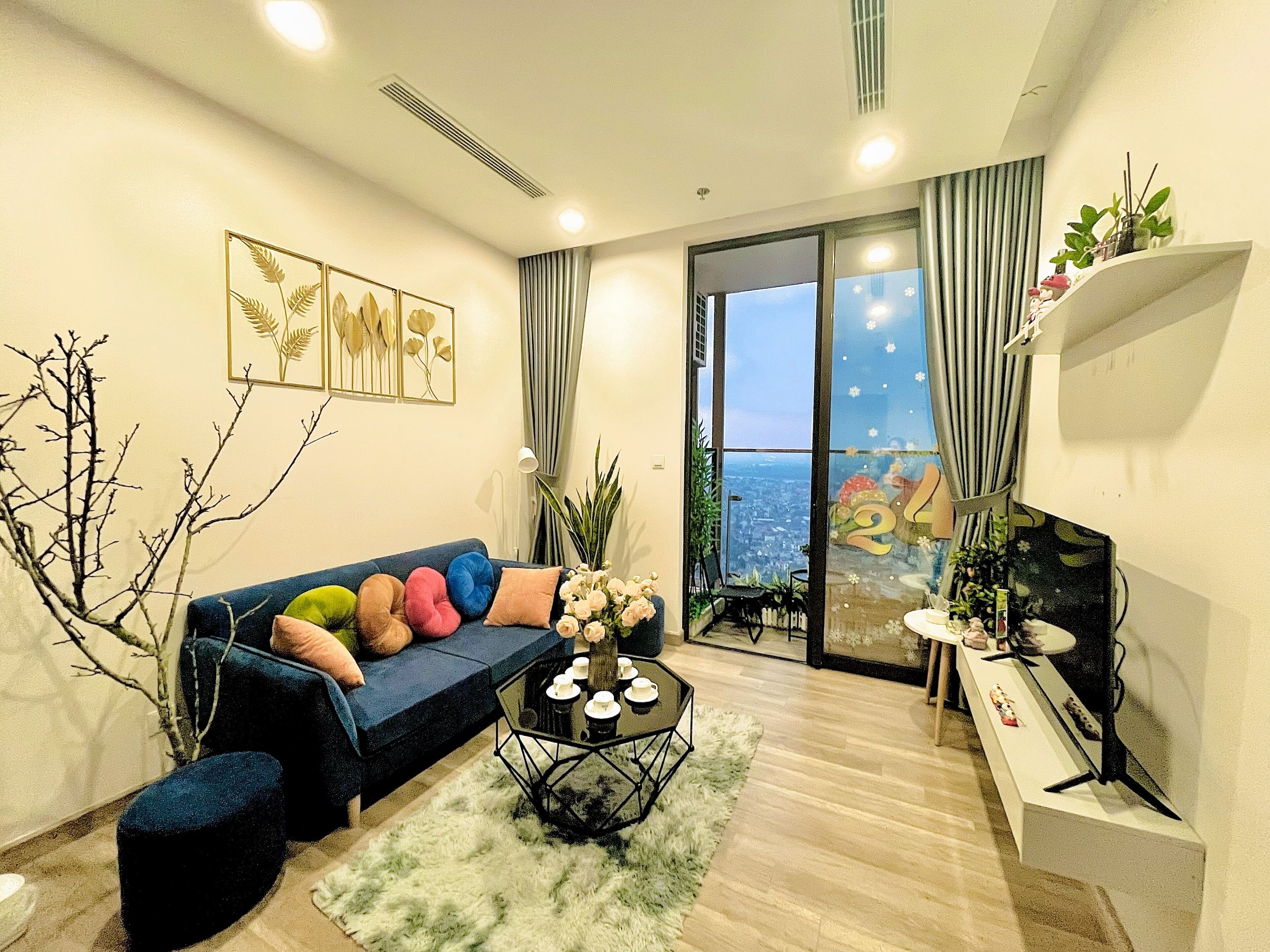 Ein modernes Wohnzimmer mit einer Couch, einem Couchtisch und Blick auf die Stadt durch große Fenster.