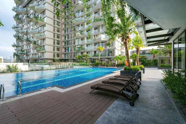 Relax by the rooftop pool surrounded by a deck and lounge chairs.