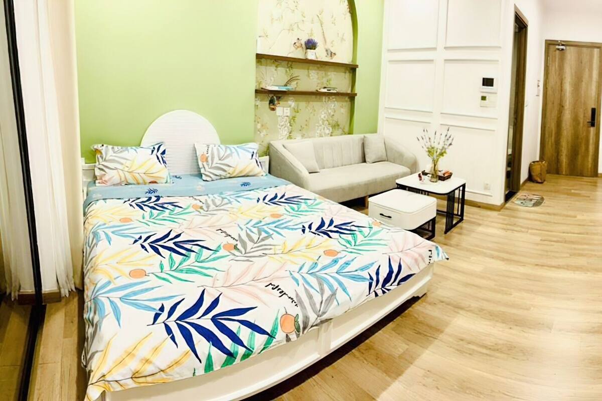 Quarto de hotel moderno com uma cama, um sofá, uma televisão e uma mesinha.