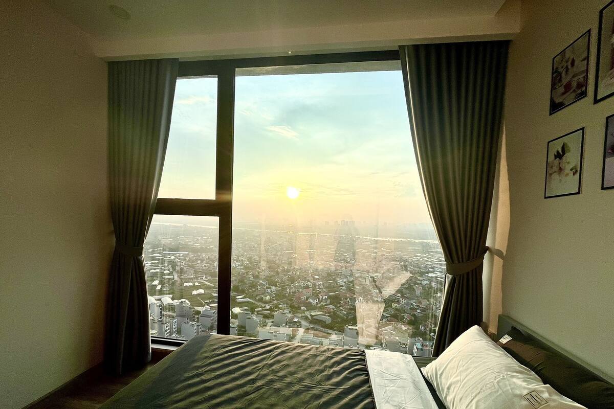 Quarto com uma janela grande, uma cama e cortinas.