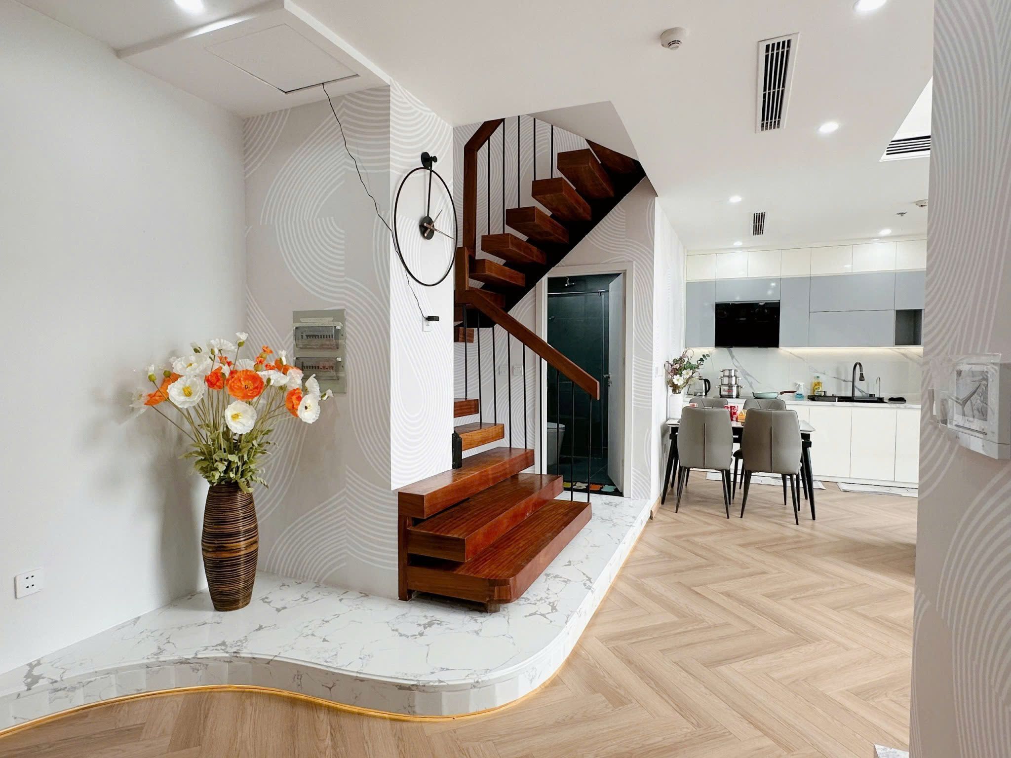 Un interior moderno con una escalera de madera, una encimera de mármol y un comedor.