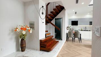 Un interior moderno con una escalera de madera, una encimera de mármol y un comedor.